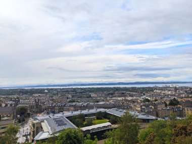 Edinburgh, İskoçya - 15 Temmuz 2025: Yükseltilmiş bir perspektif, şehrin silueti ve Waverley İstasyonu 'nun tarihi mimarisini, Forth' un Firth of Forth 'u ifade eden bulutlu bir gökyüzünün altında görüntüler.