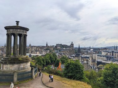 Edinburgh, İskoçya - 15 Temmuz 2025: Calton Hill 'den gelen panoramik şehir manzarası bulutlu bir gökyüzünün altında Edinburgh Şatosu ile Eski ve Yeni Kentler' e bakan Dugald Stewart Anıtı