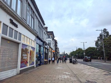 Edinburgh, İskoçya, İngiltere - 15 Temmuz 2025: Princes Caddesi 'ndeki kaldırımda yürüyen yayalar, bulutlu bir gökyüzünün altındaki tarihi Eski Şehir siluetine doğru bakan büyük bir alışveriş caddesi.