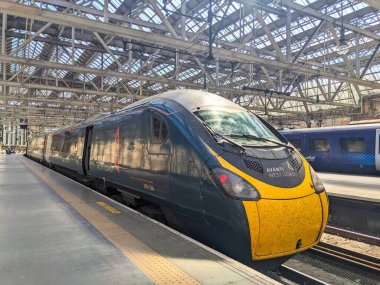 Glasgow, İskoçya - 12 Temmuz 2025: Glasgow Merkez İstasyonu 'ndaki platformda bekleyen modern bir Avanti Batı Yakası Pendolino treni, Victoria döneminden kalma özel kemerli cam çatısına sahip büyük bir demiryolu merkezi.