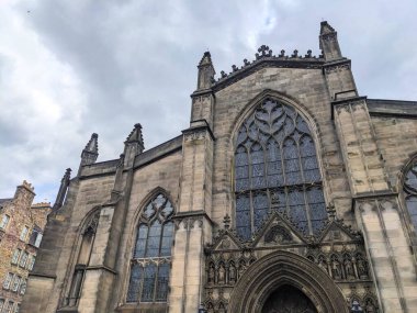 Edinburgh, İskoçya - 17 Temmuz 2025: Bulutlu bir gökyüzünün altındaki Kraliyet Mil 'ine tarihi Gotik cephesi ve St. Giles Katedrali' nin karmaşık taş oymalarının düşük açılı görüntüsü