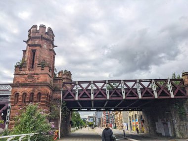 Glasgow, İskoçya, İngiltere - 14 Temmuz 2025: Bir kişi bulutlu bir gökyüzü altında ikonik Viktorya dönemi Union Demiryolu Köprüsü 'nün altında Clyde Caddesi boyunca yürüyor