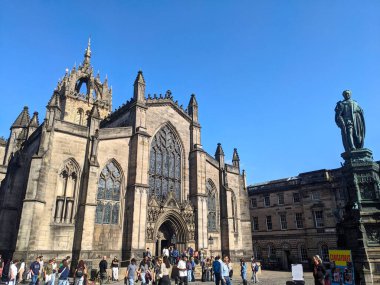 Edinburgh, İngiltere - 16 Temmuz 2025: Ziyaretçiler Parlamento Meydanı 'nda Walter Francis Montagu Douglas Scott' un yanındaki Gotik St. Giles Katedrali 'ne hayranlık duymak için toplandılar.
