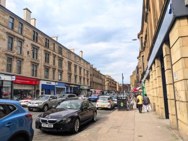 Glasgow, İngiltere - 13 Temmuz 2025: Byres Yolu 'nun günlük trafiği, kaldırımdaki yayaları ve yolu kaplayan geleneksel kumtaşı konut binalarını gösteren hareketli sahnesi