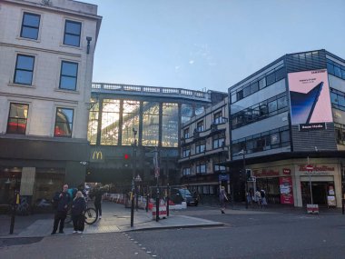 Glasgow, İngiltere - 13 Temmuz 2025: Argyle Caddesi 'nde hareketli bir şehir köşesi modern reklam panolarının akşam güneşi Hielanmans Şemsiyesi' nden geçerken Central Station 'ın Viktorya dönemi mimarisi ile tezat oluşturduğu yer