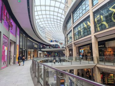 Edinburgh, İskoçya, İngiltere - 15 Temmuz 2025: Müşteriler, belirgin eğimli cam çatılı çağdaş bir alışveriş merkezi olan çok katlı St. James Quarter 'daki lüks perakende mağazalarına bakıyorlar