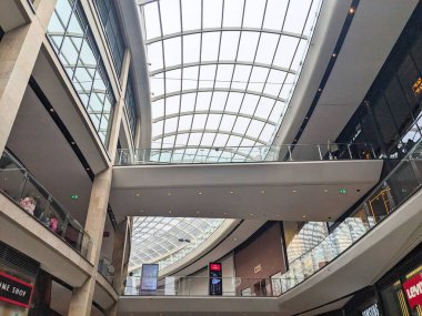 Edinburgh, İskoçya - 15 Temmuz 2025: Büyük cam bir atriyum çatısı, yaya köprüleri ve mağazaları keşfeden müşterilerin yer aldığı modern St. James Quarter alışveriş merkezinin çok katlı iç mekanı