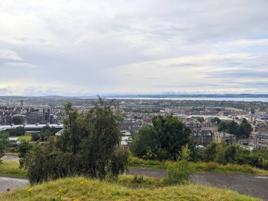 Edinburgh, İskoçya - 15 Temmuz 2025: Bulutlu bir günde Calton Hill 'den tarihi şehir silueti ve Forth' un Firth of Forth üzerinde manzaralı bir manzara