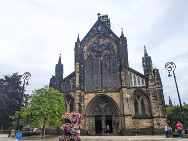 Glasgow, İskoçya - 14 Temmuz 2025: Glasgow Katedrali 'nin muhteşem ortaçağ cephesi, İskoçya Gotik mimarisinin önemli bir örneği, bulutlu bir günde girişe yakın ziyaretçilerle birlikte görülüyor