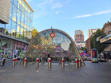 Glasgow, İngiltere - 12 Temmuz 2025: Şehir merkezindeki St Enoch metro istasyonu girişinin modern cam mimarisi, İskoçya 'da güneşli bir öğleden sonra banliyö ve yayalar ile