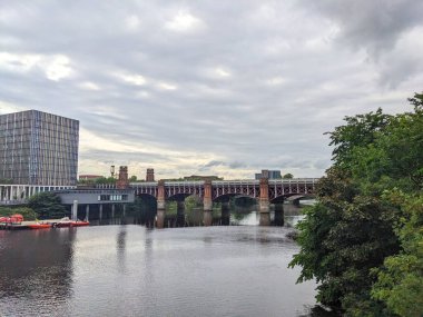 Glasgow, İskoçya - 14 Temmuz 2025: Tarihi Union demiryolu köprüsü, bulutlu bir gökyüzü altında geleneksel mimariye karşı modern ofis binalarıyla Clyde Nehri 'ni kaplıyor