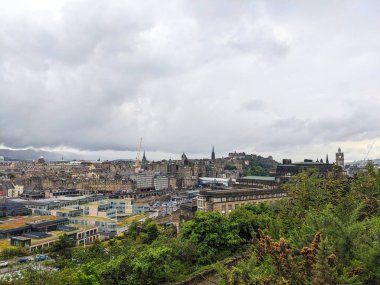 Edinburgh, İskoçya, İngiltere - 15 Temmuz 2025: Tarihi Eski Şehir mimarisi ile modern yeşil çatı binalarını çarpıcı bulutlu bir gökyüzü altında harmanlayan ünlü gökyüzü manzarası