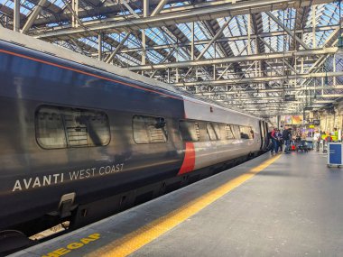Glasgow, İskoçya - 12 Temmuz 2025: Merkezi İstasyonda bir Avanti Batı Yakası treni, tarihi Viktorya döneminden kalma cam ve çelik çatı altında inen yolcularla birlikte