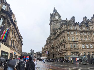 Edinburgh, İskoçya - 15 Temmuz 2025: Yayalar ve trafik bulutlu bir gökyüzü altında, tarihi Balmoral Oteli saat kulesi ve ünlü cadde üzerindeki dükkanlar boyunca ilerliyor