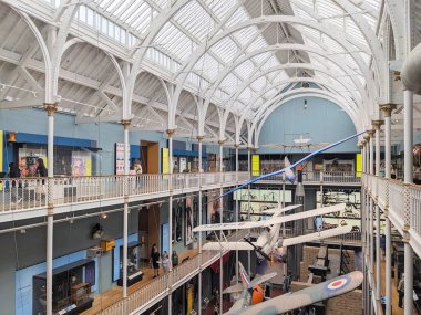 Edinburgh, İskoçya - 17 Temmuz 2025: Ziyaretçiler, Victoria dönemi dökme demir mimarisinin bir başyapıtı olan İskoçya Ulusal Müzesi 'nin güneşli Büyük Galerisi' ndeki askıya alınmış uçak ve sergilere hayran kaldılar