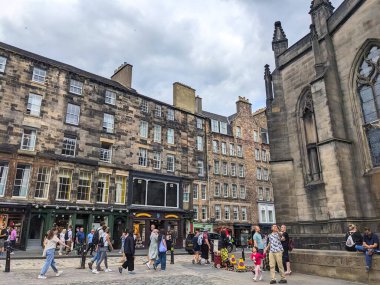 Edinburgh, İskoçya, İngiltere - 17 Temmuz 2025: İnsanlar bulutlu bir gökyüzü altında tarihi St. Giles Katedrali cephesini geçerek, Royal Miles kaldırım taşı caddesi boyunca yürürler.