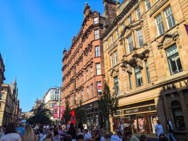 Glasgow, İskoçya - 12 Temmuz 2025: Kalabalık güneşli bir günün keyfini çıkarıyor, tarihi Viktorya dönemi kumtaşı binalarıyla dolu Buchanan Caddesi boyunca açık havada alışveriş ve yemek yiyor