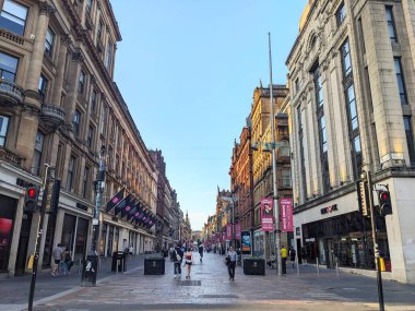 Glasgow, İngiltere - 13 Temmuz 2025: İnsanlar temiz mavi gökyüzü altında Victoria döneminden kalma tarihi kumtaşı mimarisi ile sıralanmış ünlü bir perakende satış bölgesi olan Buchanan Caddesi boyunca yürüyor