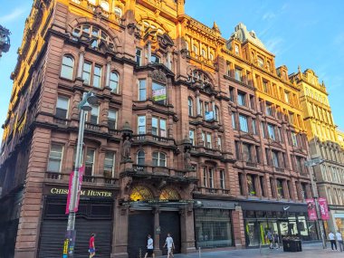 Glasgow, İskoçya - 12 Temmuz 2025: Argyll Arcade 'nin tarihi kırmızı kumtaşı cephesi yayalar şehir merkezindeki alışveriş caddesinde yürürken sıcak altın saat ışığında parlıyor