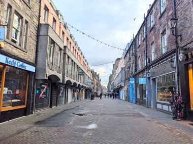 Edinburgh, İskoçya, İngiltere - 15 Temmuz 2025: Rose Caddesi 'ndeki tarihi kaldırım taşı sokağının manzarası, şehir merkezinde bulutlu bir gökyüzünün altında geleneksel mağazalar ve dairelerle kaplıydı