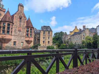 Edinburgh, İngiltere - 16 Temmuz 2025: Güneşli bir yaz gününde Dean Village 'daki tarihi Kuyu Mahkemesi ve geleneksel binaların sakin Leith Suyu' nun manzarası