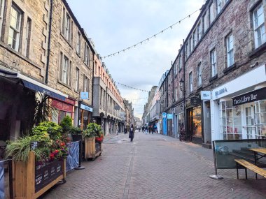 Edinburgh, İskoçya - 15 Temmuz 2025: İnsanlar bulutlu gökyüzü altındaki büyüleyici dükkanları, barları ve restoranları ile ünlü New Town 'daki tarihi Rose Caddesi boyunca yürüyorlar