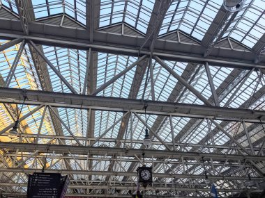 Glasgow, İskoçya, İngiltere - 13 Temmuz 2025: Büyük bir ulaşım merkezi olan Glasgow Merkez tren istasyonu içindeki karmaşık metal iskeleti ile ikonik Viktorya dönemi çelik ve cam kemerli çatısı