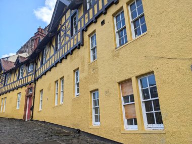 Edinburgh, İskoçya - 16 Temmuz 2025: Dekan Köyü 'nde dik bir Hawthornbank Yolu manzarası, parçalı bulutlu bir gökyüzü altında geleneksel sarı harmanlanmış ve yarı ahşap bina cephelerini gösteriyor