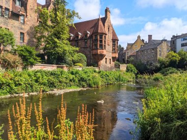 Edinburgh, İskoçya - 16 Temmuz 2025: Tarihi Kuyu Mahkemesi binası, parlak bir günde Dean Village 'ın yemyeşil sularından akan Leith' in suyuna yansıyor.