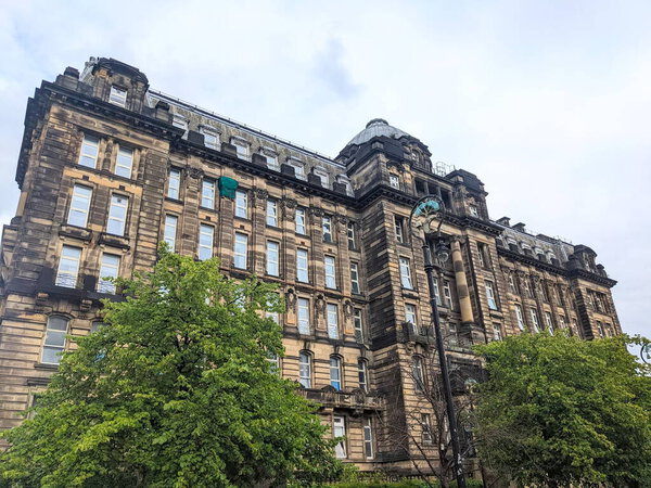 Глазго, Шотландия - 14 июля 2025 года: Низкий угол обзора внушительного неоклассического фасада исторического Королевского лазарета Глазго на соборном участке под облачным небом