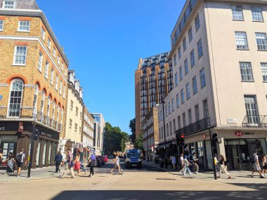 Londra, İngiltere - 17 Ağustos 2025: Marylebone bölgesindeki ünlü Baker Caddesi 'nden yayaların geçtiği yoğun bir gündüz güneşli şehir manzarası, klasik ve modern binalar tarafından mavi gökyüzü altında çerçevelendi