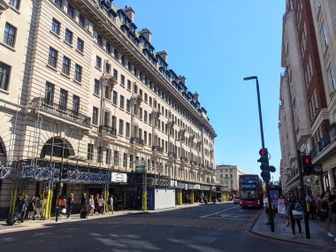 Londra, İngiltere - 17 Ağustos 2025: Güneşli Baker Caddesi 'nin kaldırımlarında yürüyen yayalar, arkasında ikonik kırmızı çift katlı bir otobüs ve Chiltern Court' un klasik mimarisi yer alıyor.