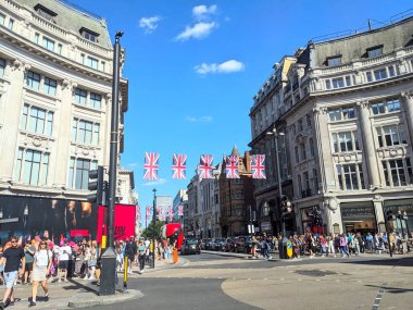 Londra, İngiltere - 09 Ağustos 2025: Oxford Sirki 'nde kalabalık yayaların alışveriş yaptığı ve neşeli Union Jack bayrağının altında karşıdan karşıya geçtiği hareketli bir sokak manzarası