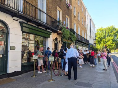 Londra, İngiltere - 17 Ağustos 2025: Mavi gökyüzü altında parlak bir yaz gününde Sherlock Holmes Müzesi 'nin 221B Baker Caddesi' ndeki kaldırımda çeşitli turist kalabalığı kuyrukta bekliyor