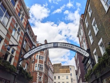 Londra, İngiltere - 09 Ağustos 2025: Carnaby Caddesi 'ndeki ikonik tabela, tarihi mimari ve mavi gökyüzü tarafından çerçevelenmiş Soho' daki ünlü yayaya ziyaretçileri karşılıyor
