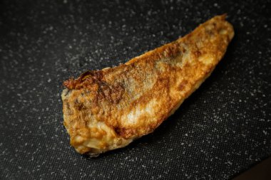 Siyah arka planda kızarmış balık fotoğrafı.