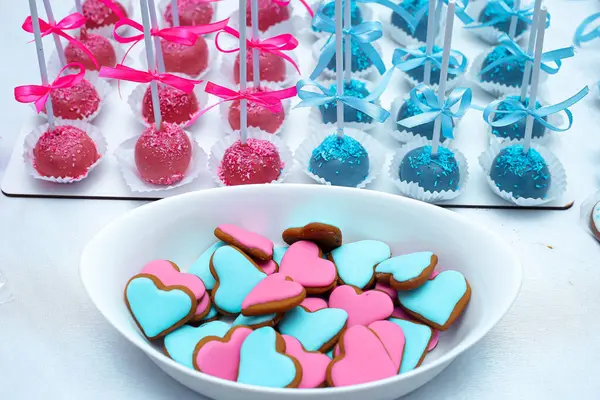 Bebek cinsiyeti, partinin pembe ve mavi süslemeleri, tatlıları, kurabiyeleri, pastaları gözler önüne serdiğini gösteriyor.