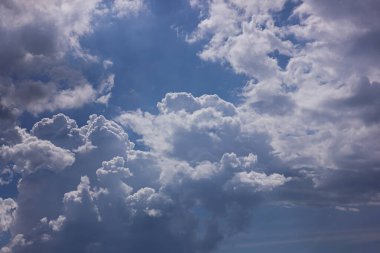Büyük, kabarık beyaz ve gri kümülüs bulutları olan mavi bir gökyüzü. Hava durumu hakkında bir doğa geçmişi..