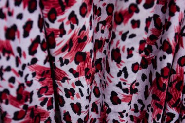 Katlanmış kumaş üzerinde kırmızı ve siyah leopar desenli yakın çekim. Moda ve doku soyut bir arkaplan