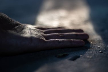 Karanlık bir sokakta, bir ışık demeti tarafından aydınlatılmış dramatik bir insan eli. Umudun, umutsuzluğun, yardımın ya da kaybın kavramsal görüntüsü.