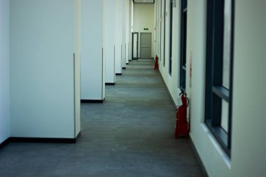 Okul binasında uzun, boş ve modern bir koridor. Kırmızı yangın söndürücüleri var. Güvenlik ve mimari kavramı