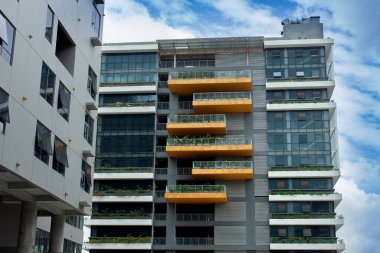 Mavi gökyüzüne karşı renkli turuncu balkonları olan modern bir apartmanın cephesi. Gayrimenkul ve kentsel yaşam kavramı
