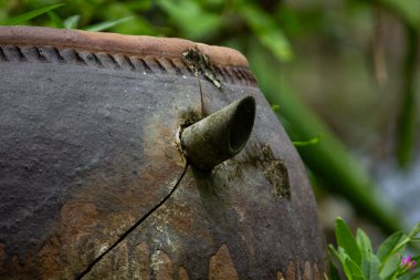 Bahçedeki eski, yosunlu, seramik bir su kavanozunun yakın çekimi. Vietnam kırsal yaşam ve nostalji kavramı