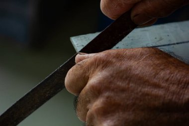 Bir zanaatkârın ellerinin, bir iş üzerinde metal bir dosya kullanarak yakın plan çekimleri. Çalışma, işçilik ve imalat kavramı.