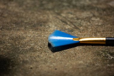 Sert bir arka planda sanatçılar için canlı bir mavi fan fırçası. Yaratıcılık, sanat ve hobiler kavramı