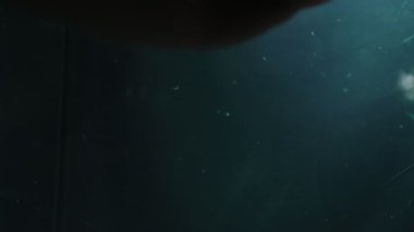 Karanlık, tozlu bir cam yüzeye baskı yapan bir insan elinin yavaş çekim kavramsal videosu. İzolasyon, korku ve tuzak kavramı