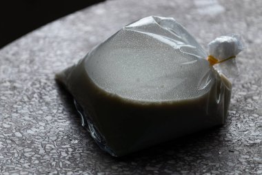 Plastik poşetteki soya sütü, Vietnam 'da popüler bir içecek, karamsar ışıklandırmalı bir terrazzo masasında oturuyor.