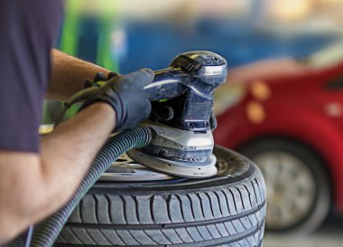 Bir araba ve boya dükkanında tekerleklerin jantlarını parlatırlar.