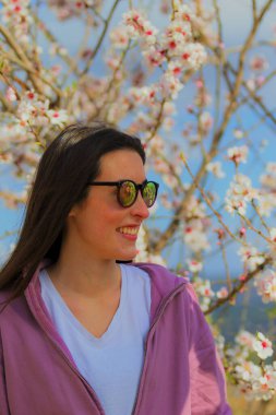 Sporcu kadın çiçek açan badem ağaçlarının arasında yürüyüşe çıkıyor.