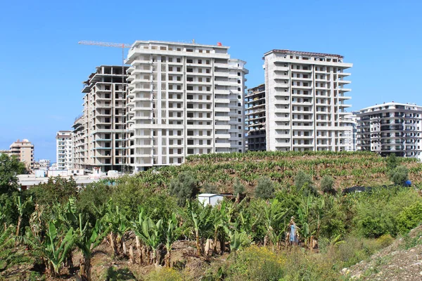 construction of an apartment building in Alanya, Turkey, against the background of a blue sky and a banana plantation